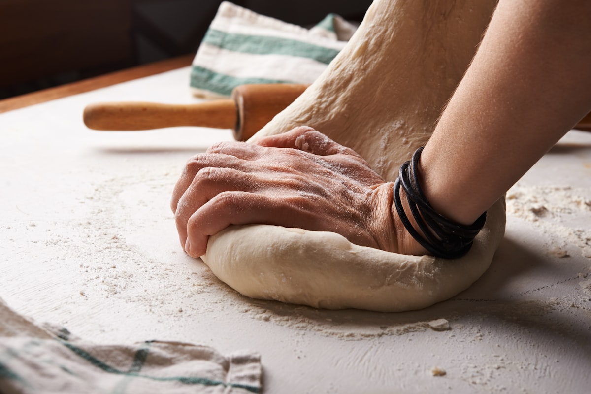 Baker dusting flour over fresh dough